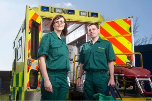 A male and female paramedic standing in front of an ambulance
