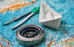Map with a paper boat and compass on it