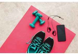 Pink exercise mat with trainers, weights and mobile phone with headphones